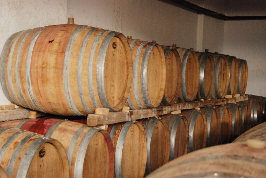 lying wine wood barrels on top of each other in a row at 'Dio Fili' cellar